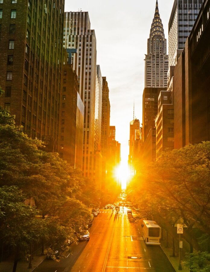 Sonnenuntergang zwischen den Hochhäusern Manhattans: Die untergehende Sonne scheint genau entlang der Ost-West-Straße und taucht die Szene in goldenes Licht – ein Naturphänomen, das als „Manhattanhenge“ bekannt ist.