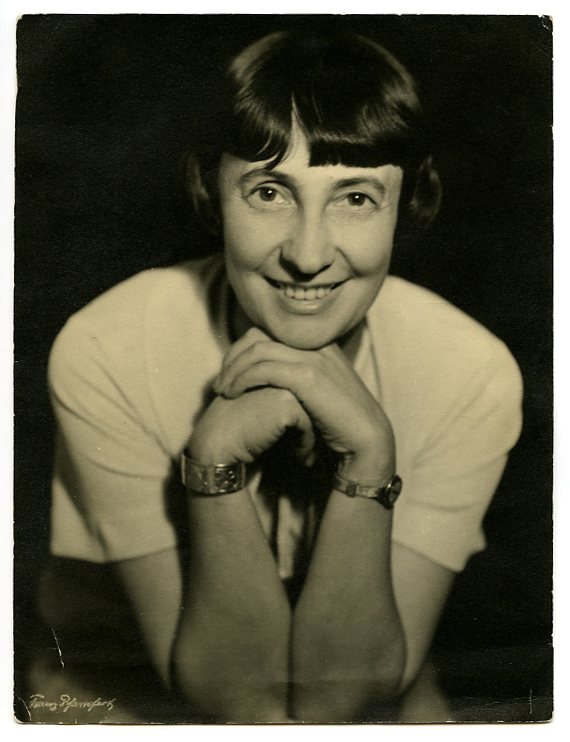 Bild: Franz Pfemfert Collection and Archiv, University of Applied Arts Vienna Das Bild zeigt Margarete Schütte-Lihotzky im Jahr 1935. Es handelt sich um eine schwarz-weiße Portraitaufnahme. Sie stützt ihr Kinn auf ihren Händen ab und lächelt direkt in die Kamera.