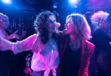 Loud & Proud: Austrian Queer Cinema / Kulturforum New York Das Bild zeigt zwei Frauen in herzlicher Umarmung, die einander tief in die Augen blicken. Ihre Kleidung und Mimik spiegeln Nähe, Humor und Spannung wider – eine Szene aus dem Film What a Feeling