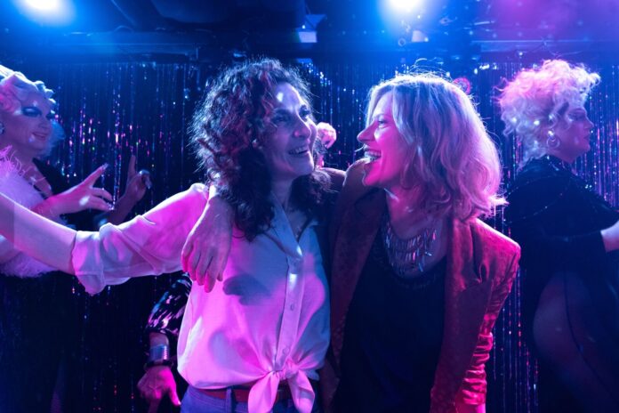 Praherfilm | Geyrhalterfilm Das Bild zeigt zwei Frauen in herzlicher Umarmung, die einander tief in die Augen blicken. Ihre Kleidung und Mimik spiegeln Nähe, Humor und Spannung wider – eine Szene aus dem Film What a Feeling