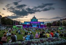 Zagreb Classic Festival / Kulturforum Zagreb Das Bild zeigt eine beleuchtete Bühne auf dem König-Tomislav-Platz in Zagreb, um die hunderten von Menschen sitzen und die klassische Musik im Sonnenuntergang genießen.