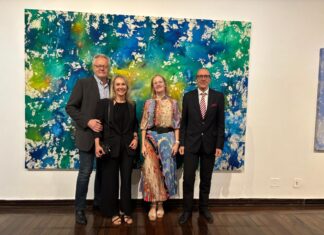 Ausstellung / Botschaft Brasilia Das Bild zeigt ein großformatiges abstraktes Kunstwerk in kräftigem Blau, Grün und Gelb und davor aufgestellt die Künstlerin Monika Kus-Picco mit Ehemann sowie Botschafter Dr. Stefan Scholz mit Ehefrau.