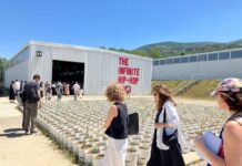 Autostrada Biennale in Prizren / Botschaft Pristina Das Bild zeigt Kunstwerk mit Blumentöpfen vor Hangar-Ausstellungsraum mit Aufschrift „The Infinite Hip-Hop Song“