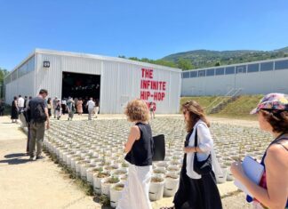 Autostrada Biennale in Prizren / Botschaft Pristina Das Bild zeigt Kunstwerk mit Blumentöpfen vor Hangar-Ausstellungsraum mit Aufschrift „The Infinite Hip-Hop Song“