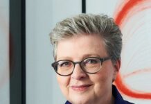 Hannah Rieger: Eine Stimme für Art Brut Auf dem Bild sieht man Hannah Rieger in Großaufnahme, sie trägt kurzes graues Haar und eine Brille und lächelt in die Kamera.