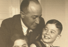 Ausstellung in Sered’ / Kulturforum Bratislava Auf dem Schwarz Weiss Bild ist die vierköpfige Familie Munk zu sehen, Der Vater im schwarzen Anzug lächelt seinem Sohn zu, der Sohn in der Lederhose, die Mutter lächelt in die Kamera und das Mädchen mit kurzen braunen Haaren lacht fröhlich.