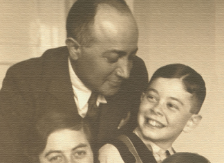 Ausstellung in Sered’ / Kulturforum Bratislava Auf dem Schwarz Weiss Bild ist die vierköpfige Familie Munk zu sehen, Der Vater im schwarzen Anzug lächelt seinem Sohn zu, der Sohn in der Lederhose, die Mutter lächelt in die Kamera und das Mädchen mit kurzen braunen Haaren lacht fröhlich.