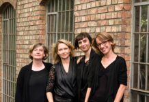 airborne extended / Kulturforum Washington Das Bild zeigt vier junge Frauen in Schwarz gekleidet vor einer Backsteinmauer.