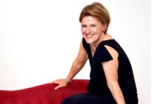 Anthologie Ukrainischer Musik / Kulturforum Berlin Das Bild zeigt Pianistin Senka Brankovic, die auf der Lehne einer roten Couch sitzt. Sie trägt ein schwarzes Kleid und lächelt in die Kamera.