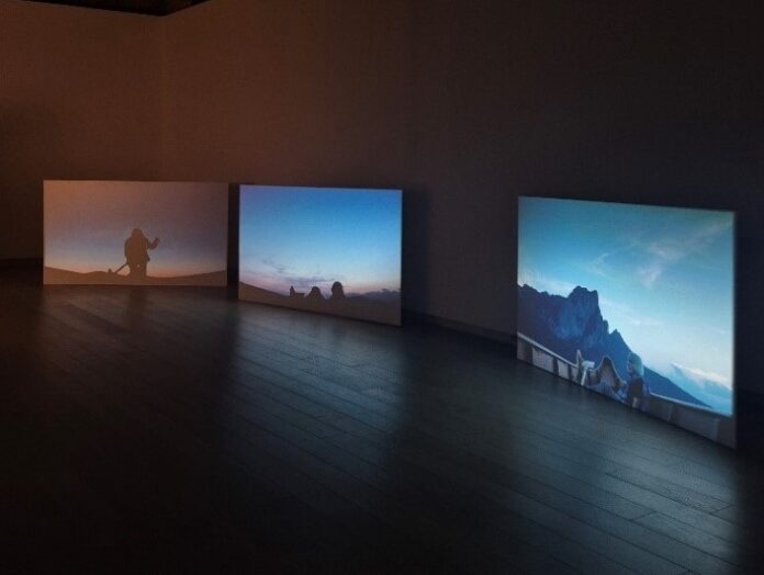 Bild: Barbara Heinzl Das Bild zeigt den Teil von Christiana Perschons Ausstellung, der sie sich mit der Künstlerin Inge Dick befasst. Dick, die sich in ihrer Arbeit vor allem mit Licht beschäftigt, wird hier von Perschon in ihrem Boot auf dem Mondsee unter verschiedenen Lichtvoraussetzungen filmisch dargestellt.