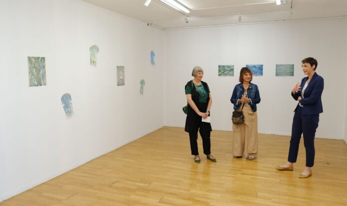 Das Bild zeigt die Künstlerinin der Galerie mit zwei weiteren Personen.