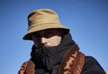 Andreas Stecher in Ghana / Podcast Interview Auf dem Bild ist Andi Stecher zu sehen. Er trägt einen braunen Schlapphut, der einen Schatten über sein Gesicht wirft. Einen dicken schwarzen Anorak und einen braunen Schal.