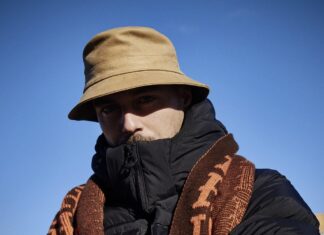 Andreas Stecher in Ghana / Podcast Interview Auf dem Bild ist Andi Stecher zu sehen. Er trägt einen braunen Schlapphut, der einen Schatten über sein Gesicht wirft. Einen dicken schwarzen Anorak und einen braunen Schal.