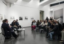 Buchpräsentation „Motherland hears, Motherland knows“ / Fotohof Salzburg Das Bild zeigt vorne die Künstlerin, Herrn Staatssekretär Schellhorn, Frau Rabl-Stadler und noch einen Künstler, die miteinander sprechen. Davor das interessierte Publikum, sitzend, ca 30 Personen, an den Wänden die Fotografien.