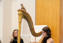 Harfenkonzert mit NASOM- Musikerin Elisabeth Plank / Kulturforum Bratislava Auf dem Bild ist die Musikerin auf der Harfe spielend zu sehen. Dahinter sitzt Beata Greneche mit einem Buch vor ihr.