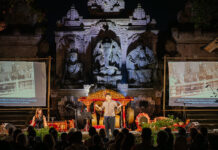 Empire – Rooting for the Antihero / Botschaft Jakarta Das Bild zeigt die Szene des Stücks in Ubud aus der Zuseherperspektive vor einer beeindruckenden javanischen Tempelkulisse. Im Zentrum ist der Schauspieler Marten Schmidt als Erzähler, links die Musikerin Anna Anderluh, rechts der Musiker Xinwei Thow und dahinter das Gamelan Orchester.