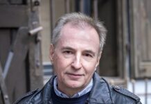 Alois Hotschnig: „Der Silberfuchs meiner Mutter” Das Bild zeigt ein Portrait von Alois Hotschnig. Er trägt eine schwarze Lederjacke, darunter einen Wollpullover und ein Hemd, seine Haare sind grau meliert, er lächelt in die Kamera.