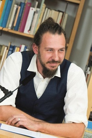 Bernhard Strobel sitzt bei einer Lesung und liest aus seinen Texten vor.