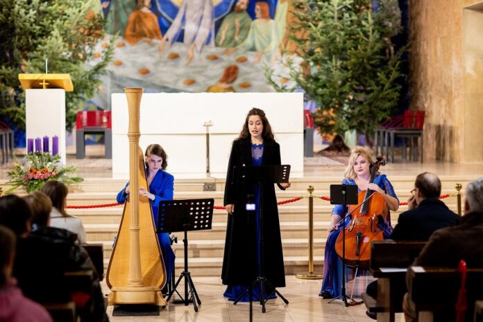 Das Bild zeigt drei Musikerinnen beim Konzert in einer Kirche - eine Harfenistin links, eine Sängerin in der Mitte und eine Cellistin rechts.