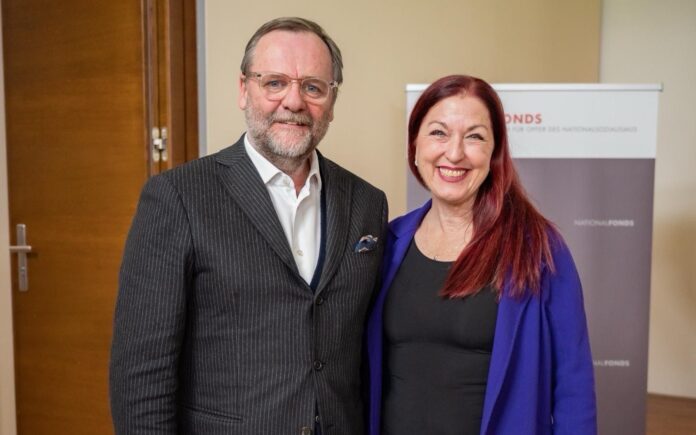 Auf dem Bild sieht man Sepp Schellhorn und Hannah Lessing nebeneinander stehend und lächelnd in die Kamera blicken.