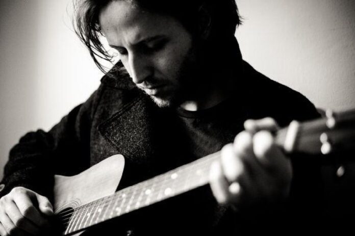 Schwarz-weiß-Porträt des Musikers Moritz Gamper mit Gitarre