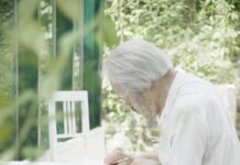 Konzert „100. Geburtstag Friedrich Cerha“ / Kulturforum Bratislava Das Bild zeigt einen alten Mann in einem Garten sitzend über eine Partitur gebeugt