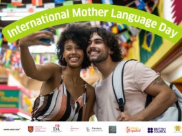 Sprachenschwerpunkt / Kulturforum Pretoria Das Bild zeigt in der Mitte und sehr präsente zwei junge Menschen (Frau und Mann), die ein Selfie machen, darüber steht in großen Lettern und im Halbkreis: „International Mother Language Day“; dahinter kann man sehr verschwommen eine Gasse mit vielen bunten Fahnen sehen. Darunter sind viele Logos der teilnehmenden Institutionen zu sehen, darunter Österreichische Botschaft und Österreichisches Kulturforum Pretoria.