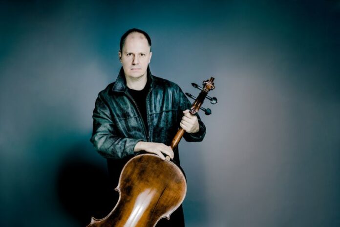 Bild: Andrej Grilc Das Bild zeigt den Musiker Giovanni Gnocchi mit seinem Cello vor einem blauen Hintergrund.