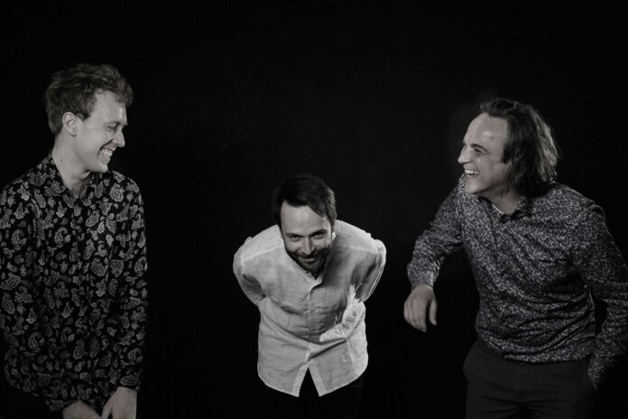 Das Bild zeigt das Trio Dusha Connection in einer Schwarz-Weiß-Aufnahme. Die Musiker Esad Halilovic (rechts) und Urs Hager (links) lachen sich gegenseitig an, während Clemens Rofner (mitte) vornübergebeugt verschmitzt in die Kamera lächelt.
