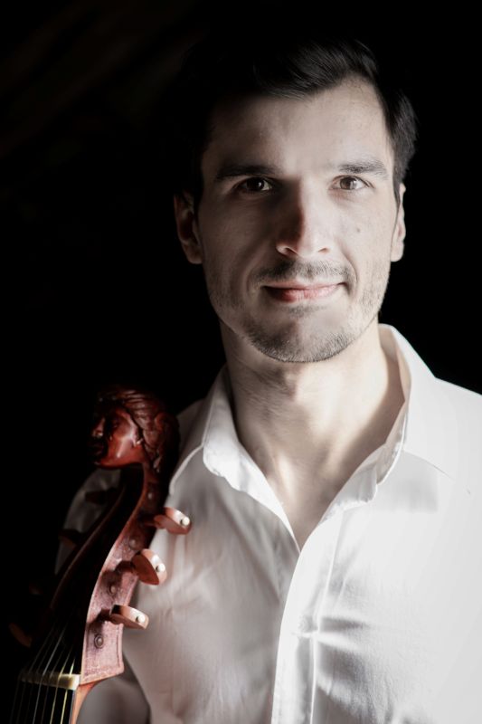 Das Bild zeigt den Musiker Christoph Urbanetz mit seiner Gambe vor einem schwarzen Hintergrund.