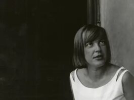 100 Jahre Ingeborg Bachmann / Botschaft Oslo Schwarzweißporträt der Schriftstellerin Ingeborg Bachmann. Sie sitzt seitlich vor einem dunklen Hintergrund und trägt ein ärmelloses, helles Kleid. Ihre Frisur, ein kurzer, glatter Bob umrahmt das Gesicht. Bachmann blickt nach oben rechts außerhalb des Bildausschnitts, ihr Ausdruck wirkt nachdenklich und konzentriert.