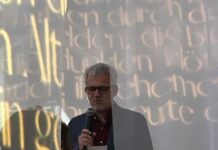 EUNIC – Welttag der Poesie / Botschaft Algier Das Bild zeigt den von Schleiern umgebenen Botschafter beim Lesen eines Trakl-Gedichts