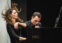 Piano Duo Gugg / Kulturforum Washington Das Bild zeigt das Piano Duo Gugg. Der Musiker sowie die Musikerin sitzen am Flügel und spielen energisch und passioniert darauf.