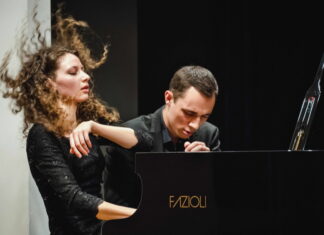 Piano Duo Gugg / Kulturforum Washington Das Bild zeigt das Piano Duo Gugg. Der Musiker sowie die Musikerin sitzen am Flügel und spielen energisch und passioniert darauf.