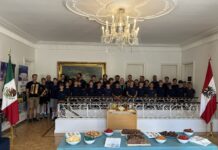 St. Florianer Sängerknaben / Kulturforum Mexiko Die St. Florianer Sängerknaben stehen in einem festlichen Raum mit Kronleuchter, Möbeln und Teppichen. Im Hintergrund sind die Flaggen Österreichs und Mexikos zu sehen.