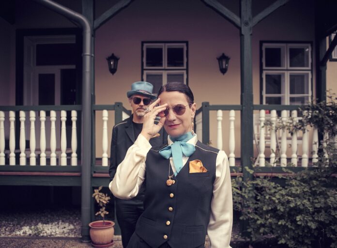 Das Bild zeigt die Mitglieder von Fox On Ice, Anna Luca Poloni und Christian Mair, die vor einem Haus mit Terrasse stehen.