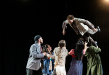 Šibenik Dance Festival / Kulturforum Zagreb Das Bild zeigt eine Tanzgruppe in bunten Kostümen auf der Bühne und eine Person wird in die Luft geworfen.