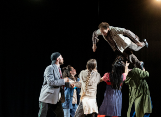 Šibenik Dance Festival / Kulturforum Zagreb Das Bild zeigt eine Tanzgruppe in bunten Kostümen auf der Bühne und eine Person wird in die Luft geworfen.