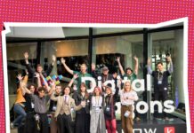 Frau Perchta / Kulturforum Warschau Das Bild zeigt eine Gruppe junger Entwicklerinnen und Entwickler sowie Projektbeteiligte vor dem Eingang von Digital Dragons in Krakau. Die Personen stehen vor dem Logo der Konferenz und winken in die Kamera.