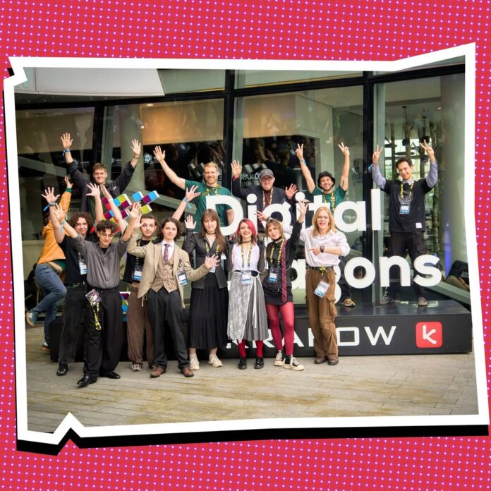 Bild: Österreichisches Kulturforum Warschau Das Bild zeigt eine Gruppe junger Entwicklerinnen und Entwickler sowie Projektbeteiligte vor dem Eingang von Digital Dragons in Krakau. Die Personen stehen vor dem Logo der Konferenz und winken in die Kamera.