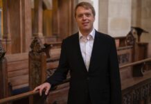 Stefan Donner / Kulturforum Washington Der Organist Stefan Donner inmitten kunstvoll geschnitzter dunkler Kirchenbänke.
