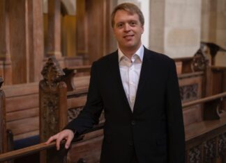Stefan Donner / Kulturforum Washington Der Organist Stefan Donner inmitten kunstvoll geschnitzter dunkler Kirchenbänke.