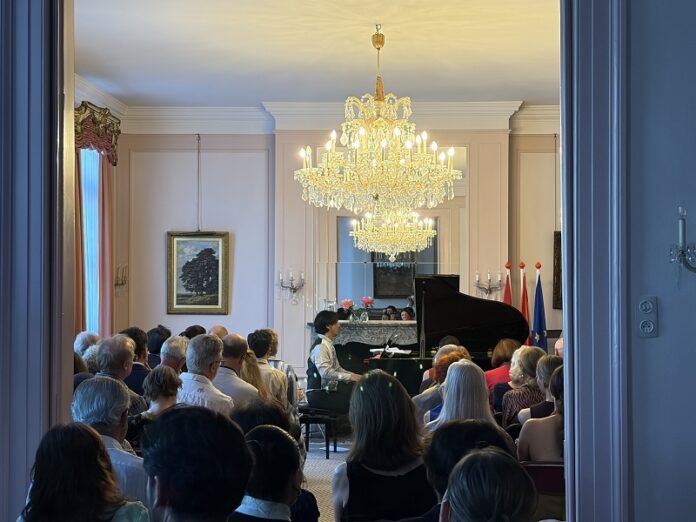 Das Bild zeigt den Pianisten und Komponisten Hyung-ki Joo, der in der österreichischen Residenz vor Publikum Klavier spielt.