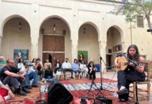 Avin Ahmadi Tournee / Botschaft Rabat Das Bild zeigt die Musikerin Avin Ahmadi, die vor einem Publikum im Innenhof eines traditionellen marokkanischen Gebäudes Oud spielt
