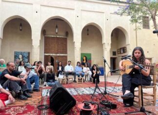 Avin Ahmadi Tournee / Botschaft Rabat Das Bild zeigt die Musikerin Avin Ahmadi, die vor einem Publikum im Innenhof eines traditionellen marokkanischen Gebäudes Oud spielt