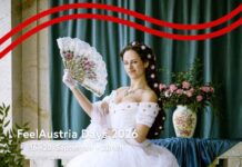 FeelAustria Days / Kulturforum Bern Das Bild ist das Werbemotiv der FeelAustria Days 2026. Zu sehen ist eine moderne Parodie auf Kaiserin Sissi: Eine Person steht in einem weißen, prunkvollen Kleid vor einer kunstvoll gestalteten Kulisse im Barockstil. Sie hält einen Fächer in der Hand und posiert bewusst unkonventionell. Ihr Gesichtsausdruck wirkt lässig und leicht übertrieben, mit einem kleinen, schelmischen Zug, während sie direkt in die Kamera blickt. Im Vordergrund steht in weißer Schrift der Text: „FeelAustria Days 2026 – Von 16. bis 20. September in Zürich“.