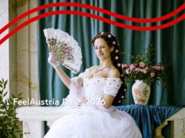 FeelAustria Days / Kulturforum Bern Das Bild ist das Werbemotiv der FeelAustria Days 2026. Zu sehen ist eine moderne Parodie auf Kaiserin Sissi: Eine Person steht in einem weißen, prunkvollen Kleid vor einer kunstvoll gestalteten Kulisse im Barockstil. Sie hält einen Fächer in der Hand und posiert bewusst unkonventionell. Ihr Gesichtsausdruck wirkt lässig und leicht übertrieben, mit einem kleinen, schelmischen Zug, während sie direkt in die Kamera blickt. Im Vordergrund steht in weißer Schrift der Text: „FeelAustria Days 2026 – Von 16. bis 20. September in Zürich“.