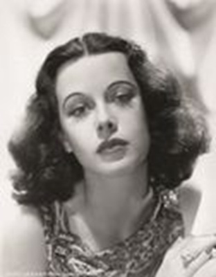 Auf dem Bild ist eine schwarzweiße Fotografie von Hedy Lamarr zu sehen, die direkt in die Kamera blickt.