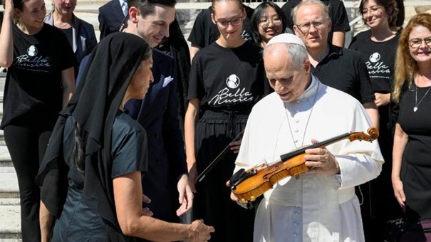 Das Bild zeigt Papst Leo XIV., welcher gerade die „Dalla Costa-Geige“ vom Jugend Ensemble Bella Musica des Pre-College der Universität Mozarteum in Salzburg überreicht bekam.