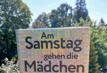 Literaturveranstaltungen Fiona SIRONIC – Botschaft Oslo Auf einem steinernen Mauersims steht im Freien das Buch Am Samstag gehen die Mädchen in den Wald und jagen Sachen in die Luft von Fiona Sironic. Das Cover ist in Gelb, Rosa, Blau und Violett gestaltet und zeigt ein pixelartiges, abstraktes Muster. Auf dem Cover steht außerdem „2025 deutscher buchpreis Shortlist“. Im Hintergrund sind unscharf grüne Bäume und blauer Himmel zu sehen.